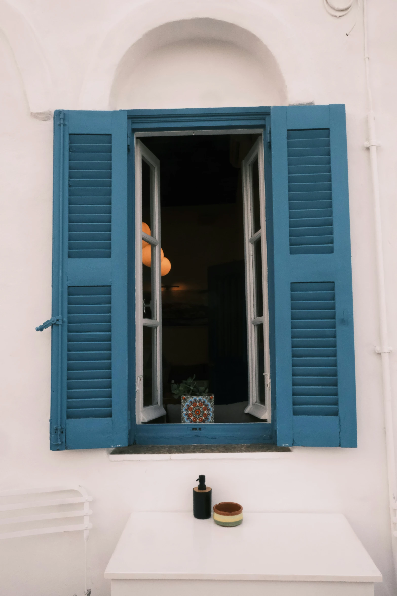 a window has blue shutters with a vase with flowers