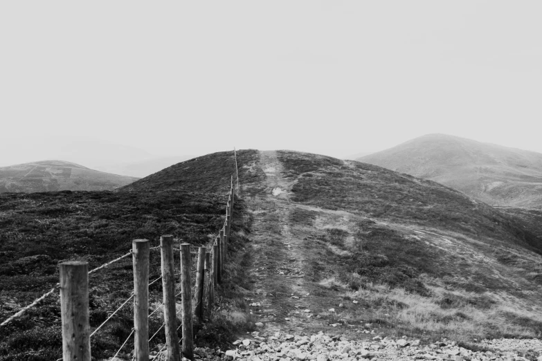 black and white pograph of mountains with a fence