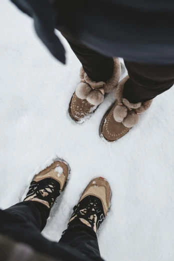 view from above of couple's feet standing in snow