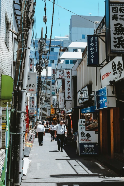 people walk down an alley way with signs on both sides