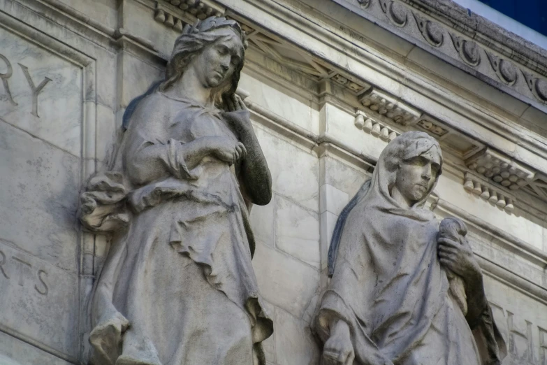 statues of women in robes next to each other on a building
