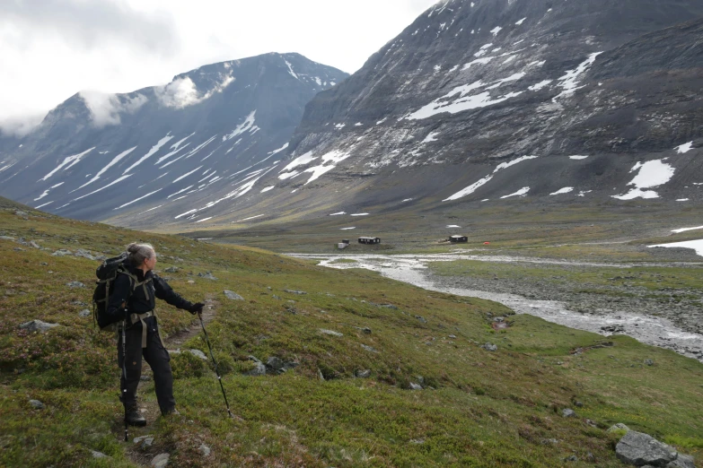 man on path surrounded by hilly area with grass and mountains