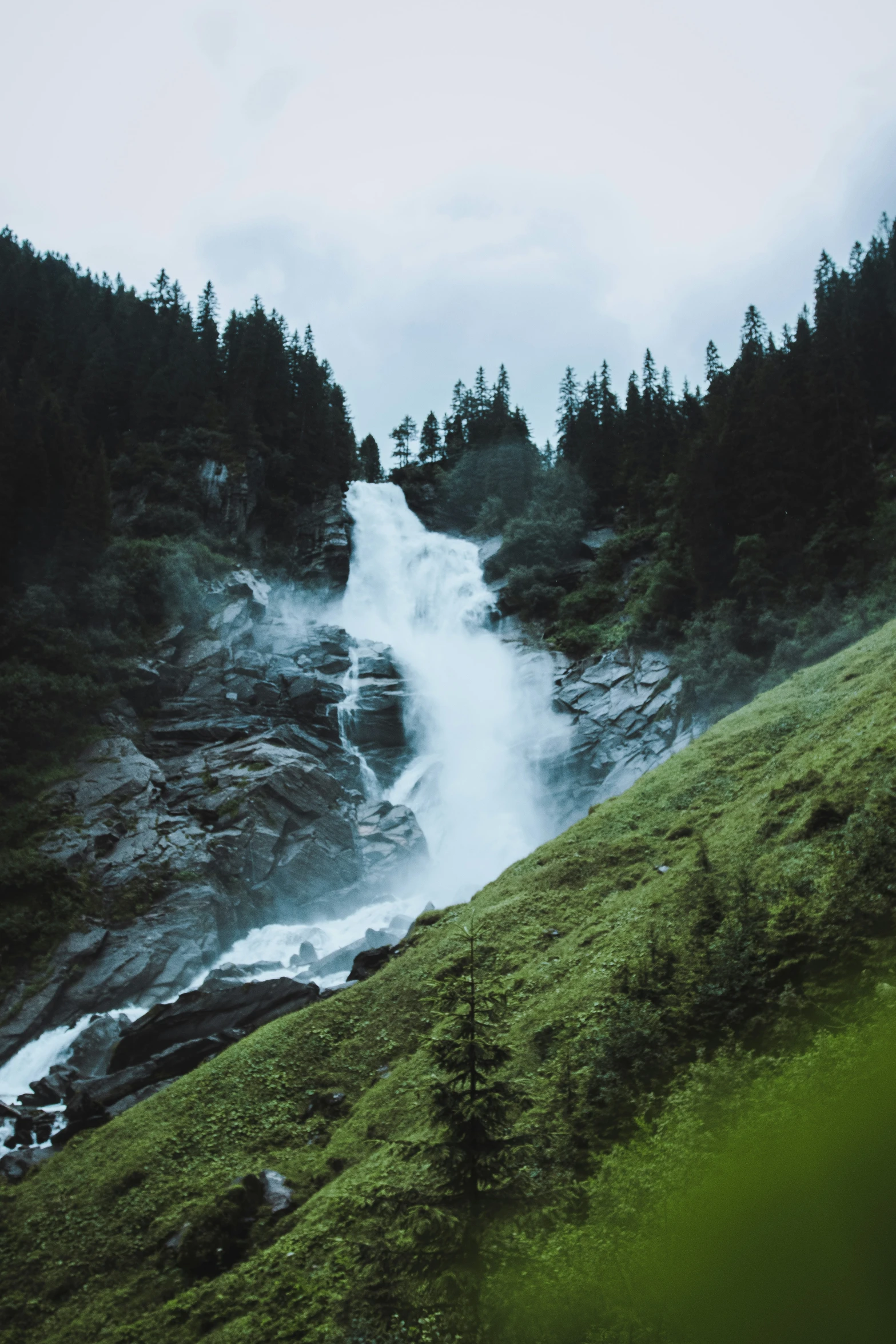 a small waterfall with green grass and trees