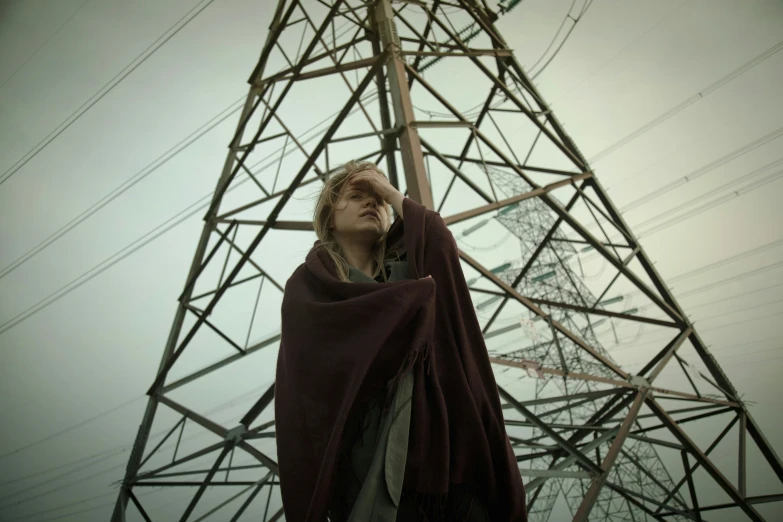 a man wearing a hooded robe is standing next to an electric tower