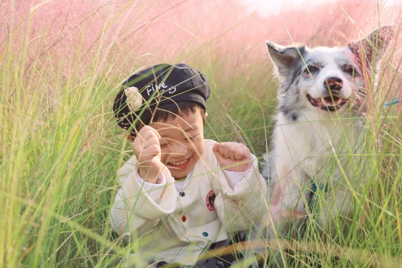 the little boy is playing with his dog in the tall grass