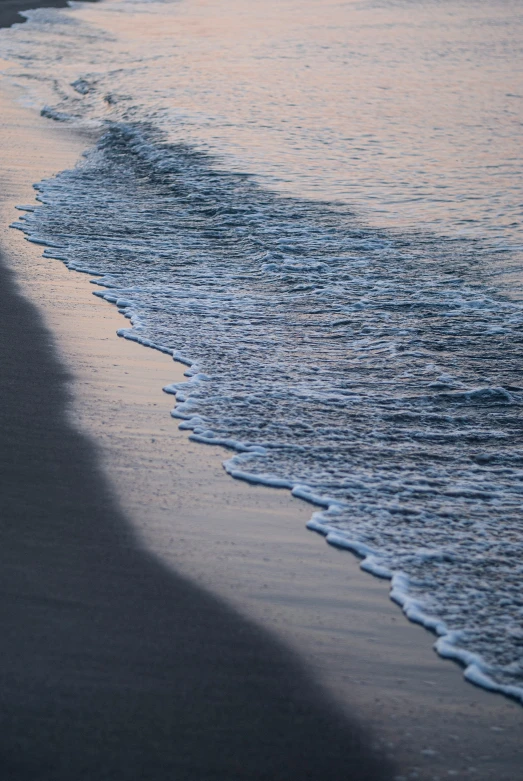 a surfboard is standing in the water near the shore