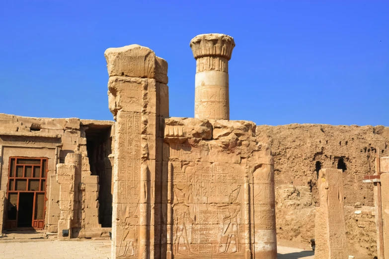 two columns and a doorway in front of a stone wall