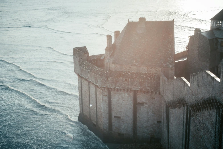 an ancient castle is in the foreground and some waves lapping on the beach