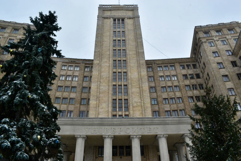 a building with some pillars and trees on the ground