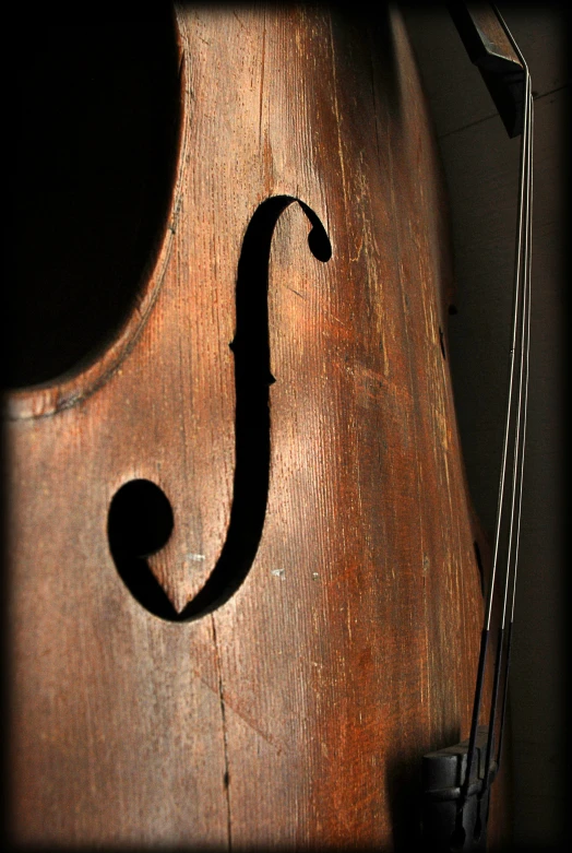 a violin is leaning on a wall, with a string hanging down