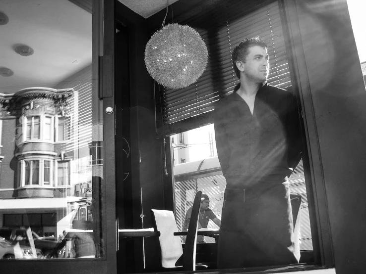 a man standing in front of a window next to a laptop