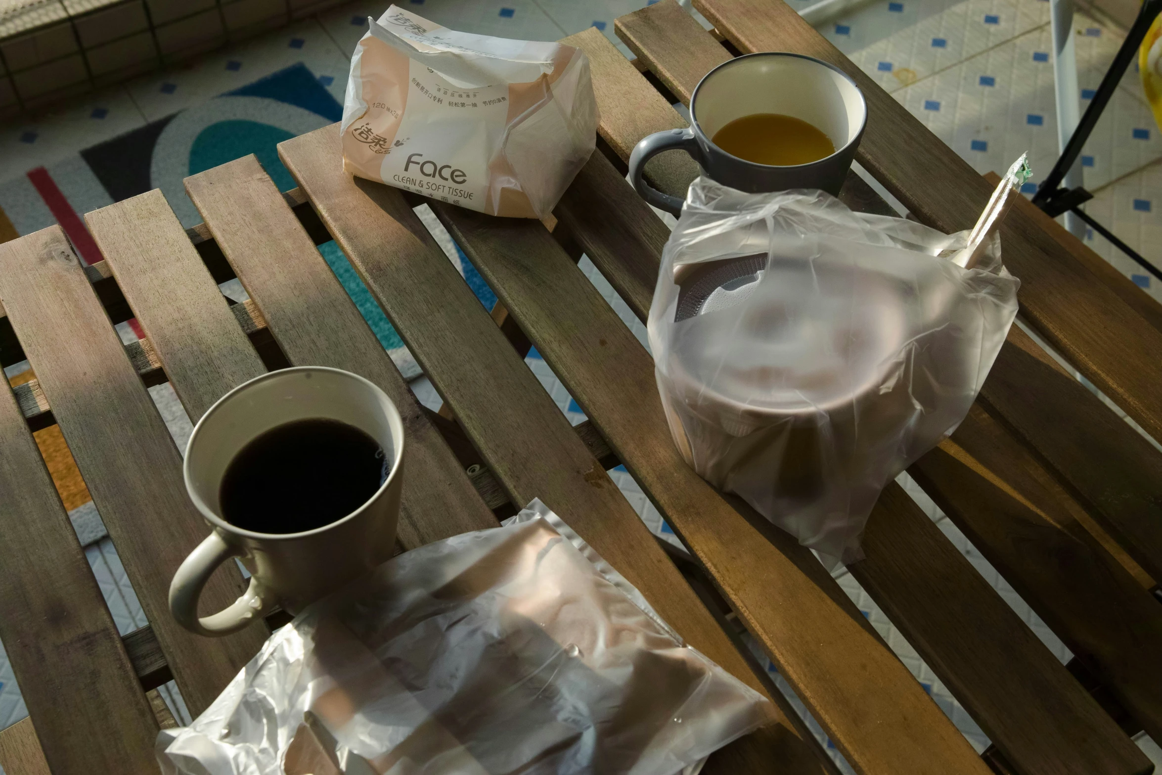 two cups of tea and a napkin on a bench