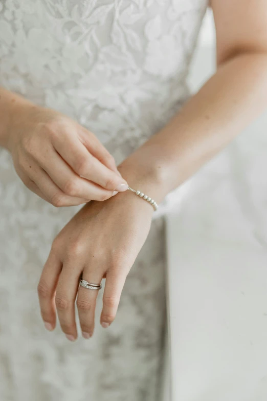 a person wearing a ring and dress holding their hands