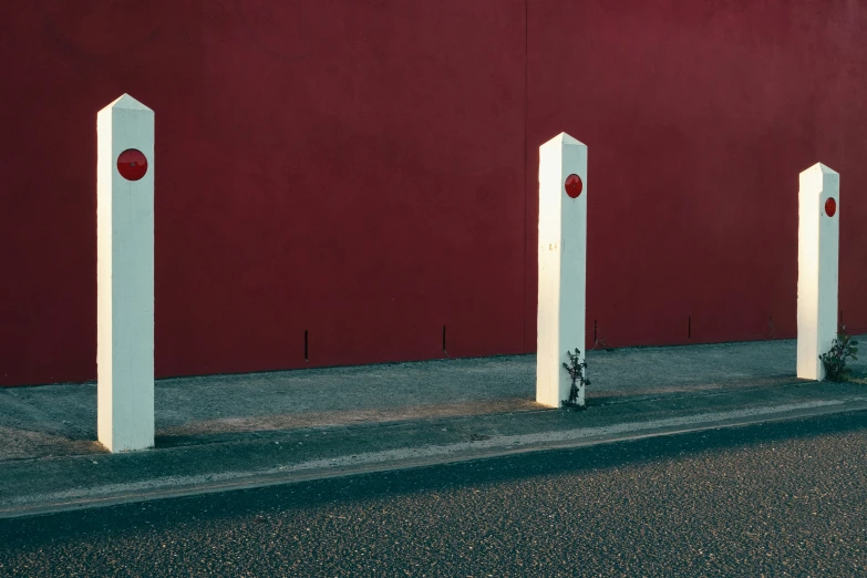 three red and white square shaped concrete posts next to a street