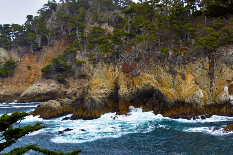 an ocean with green cliffs and trees on the shore