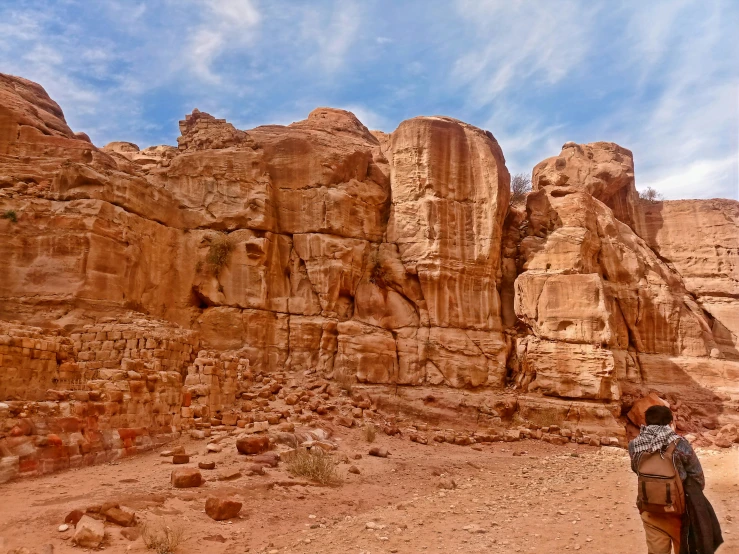 two people are walking near the large, majestic rock formation