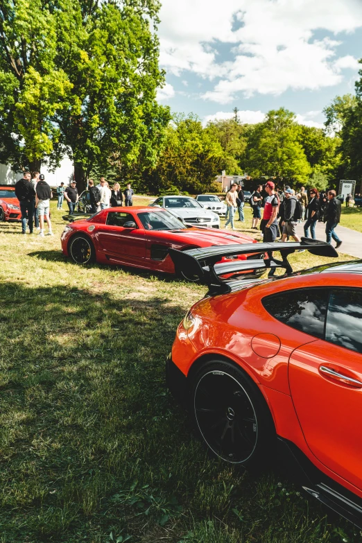 a group of red sports cars parked next to each other in front of people