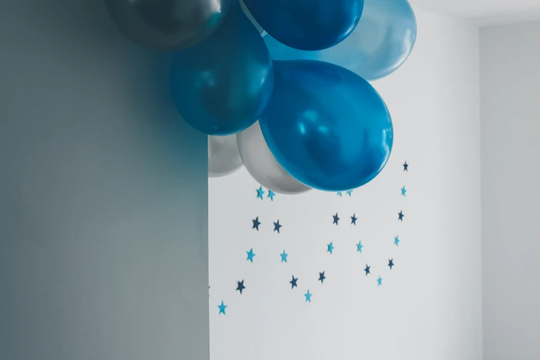 many blue and white balloons with silver stars on the wall