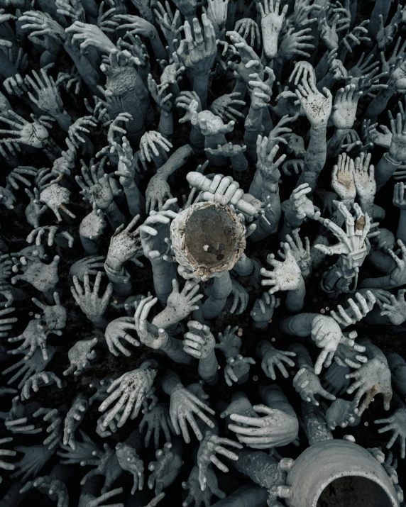 a number of people surrounding an object with many hands reaching for it