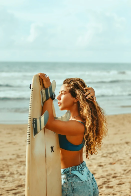 a woman wearing jeans and holding a surfboard