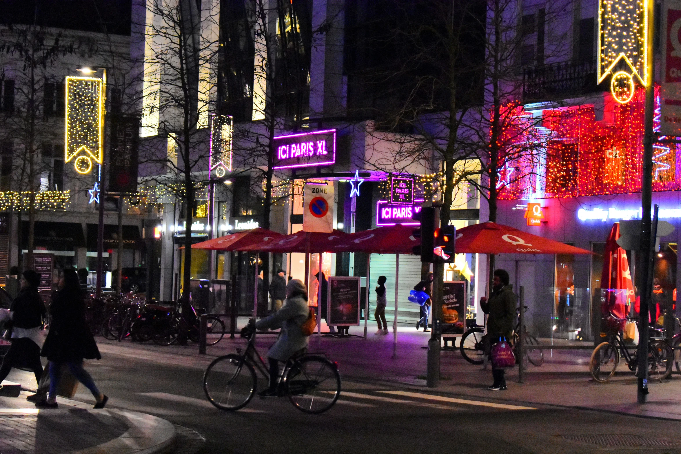 an outdoor city intersection decorated for christmas with people walking