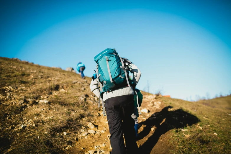 a person with a large blue backpack walking up a hill