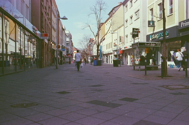 an empty city street with a pedestrian and shoppers