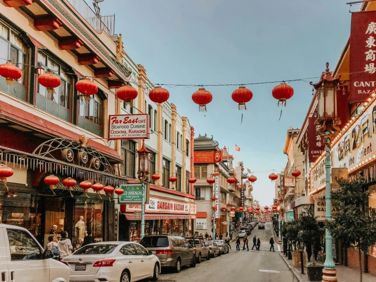 people are walking around red hanging lanterns in a street