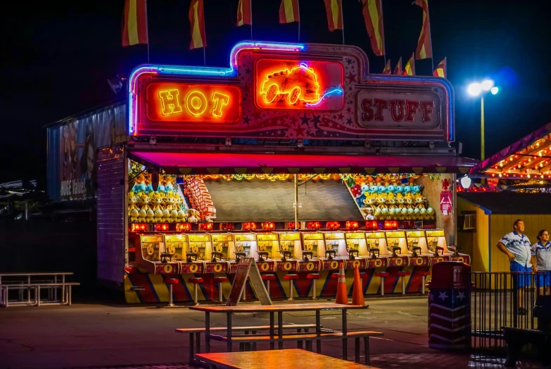 a lit up carnival with three people on benches