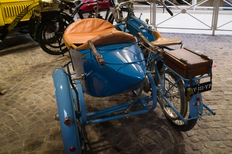 a blue vintage car is parked next to another motor cycle