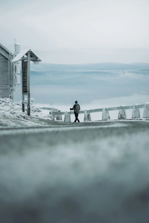 someone is standing in front of a fence with mountains and fog