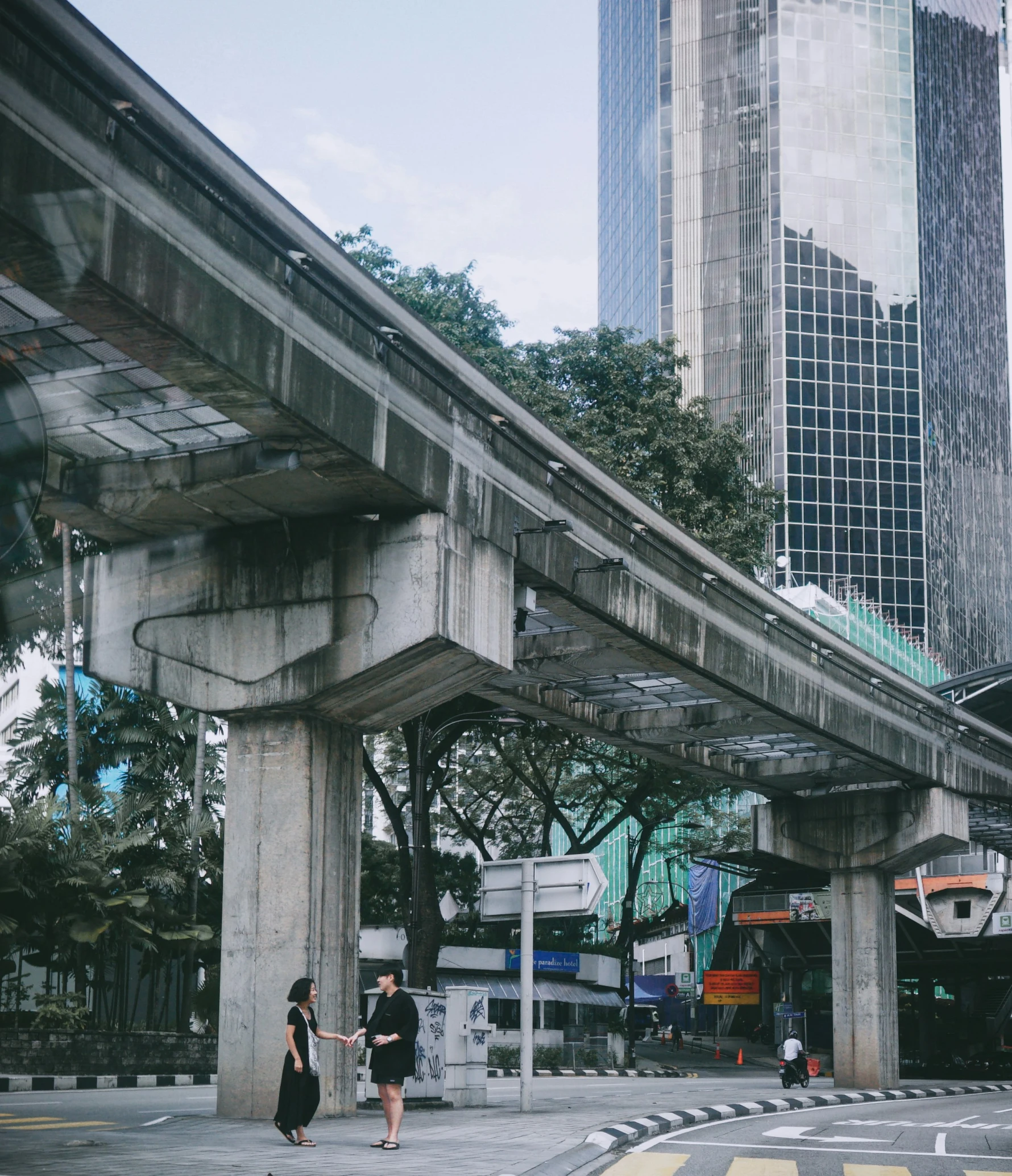 three people walking underneath an overpass in the city