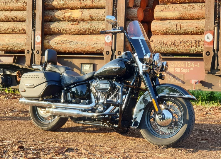 a motorcycle sits in front of large stacks of wood