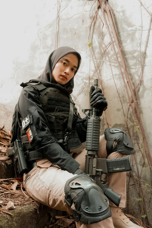 a girl kneeling on the ground holding an automatic rifle