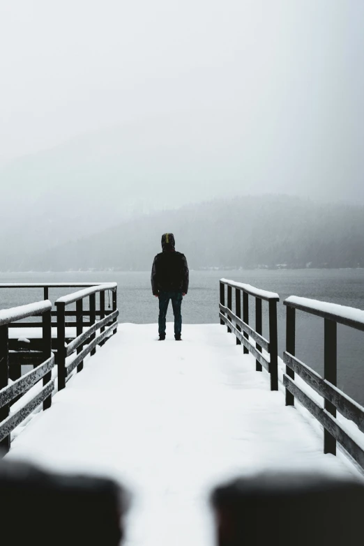 man walking out into the snow towards the water