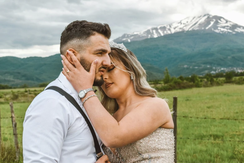 the man and woman are in a field with a mountain view