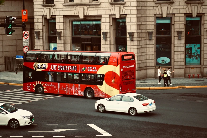 a double decker bus driving past a busy intersection