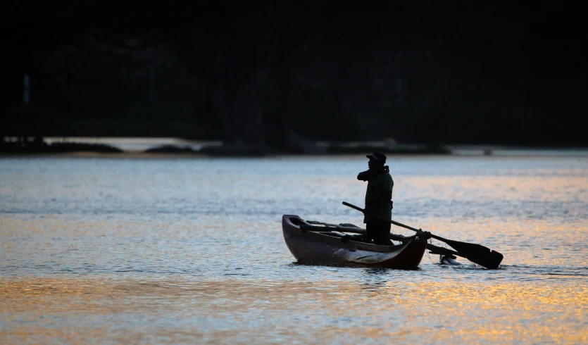 person on boat in body of water with paddle