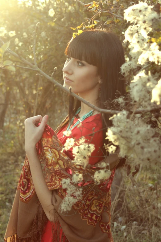 the woman is wearing a red dress near many trees