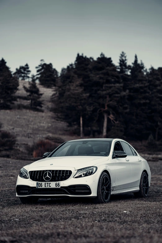 a white mercedes benz cla parked in front of a forest