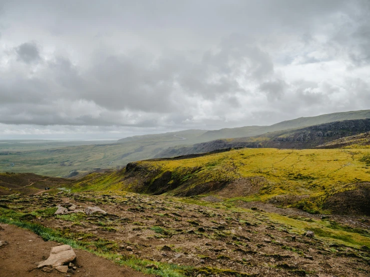 a big grassy hillside with a field and mountains in the distance