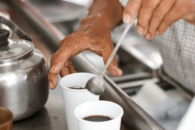 a man holding some spoons with some coffee