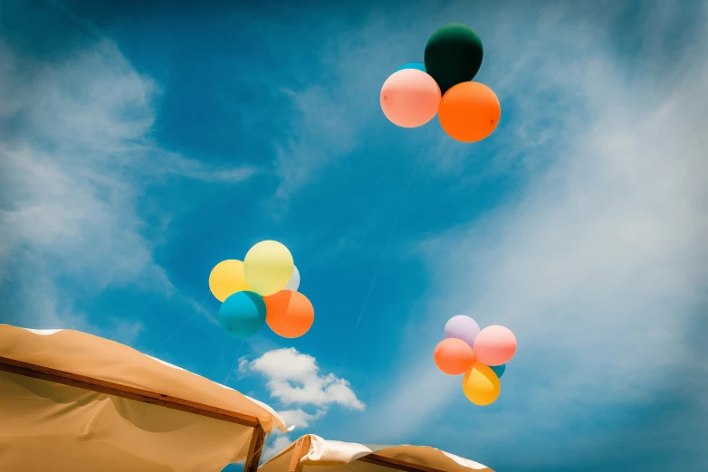 several balloons floating above a large brown umbrella