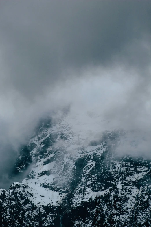 a snow covered mountain with dark gray clouds