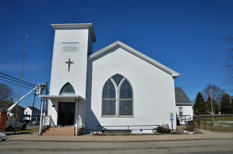 a white church with a steeple and a flag on the lawn