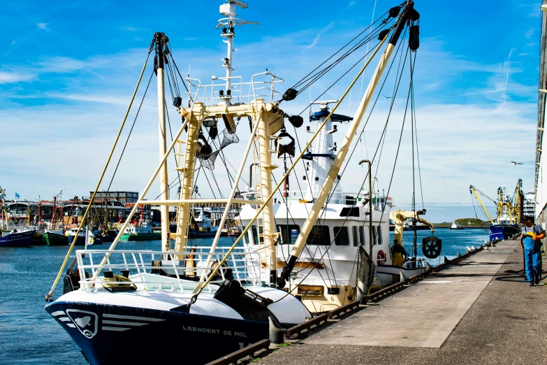 large boat moored in a harbor with people walking by