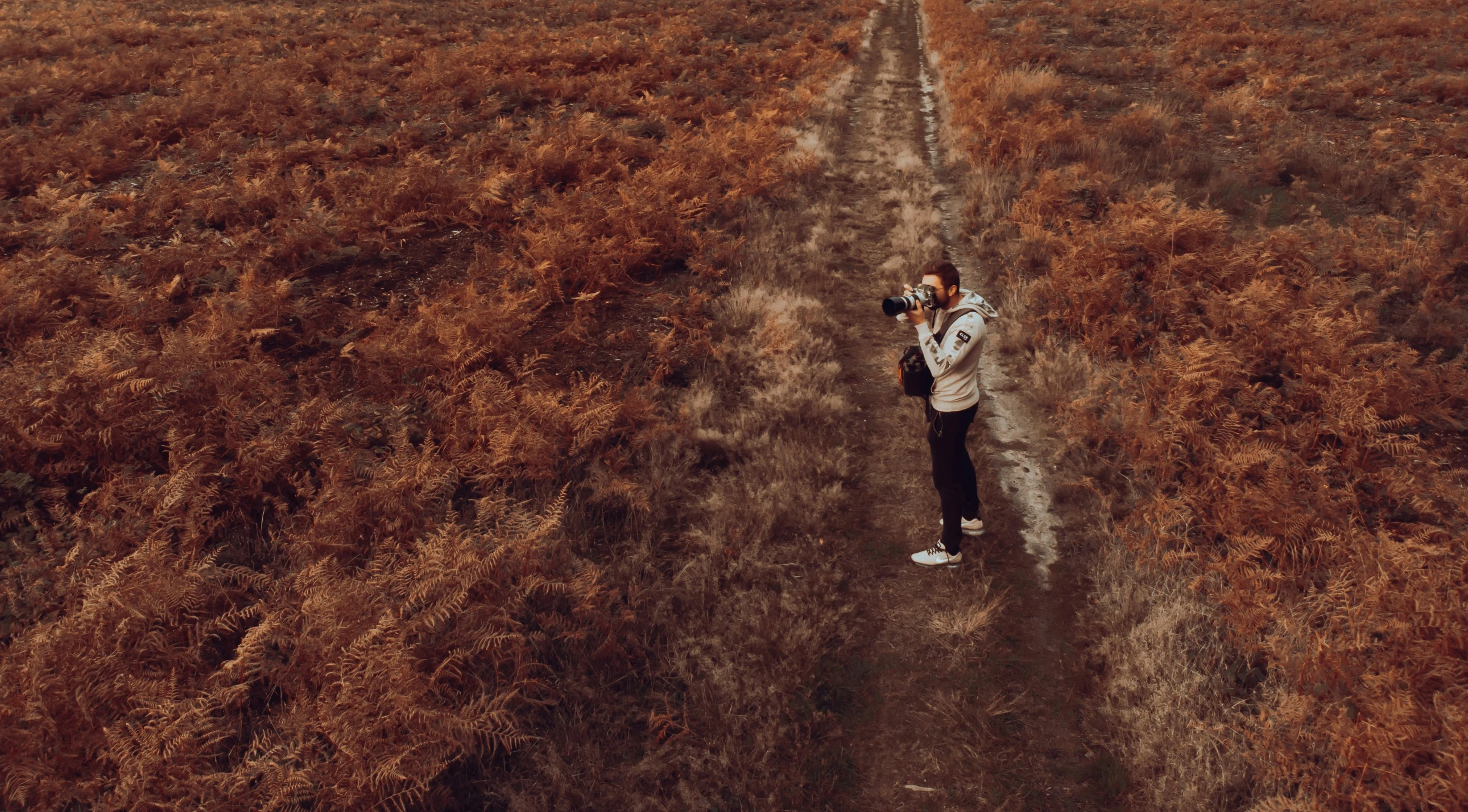 man in a field holding a camera taking a picture