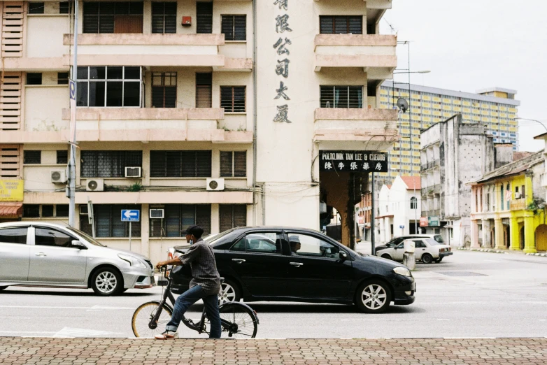 a man is riding a bike next to his black car