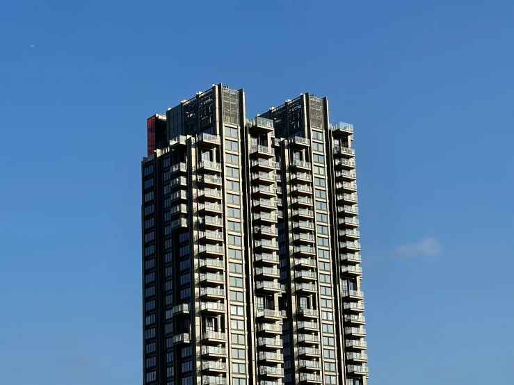 a tall building with balconies sits near the blue sky