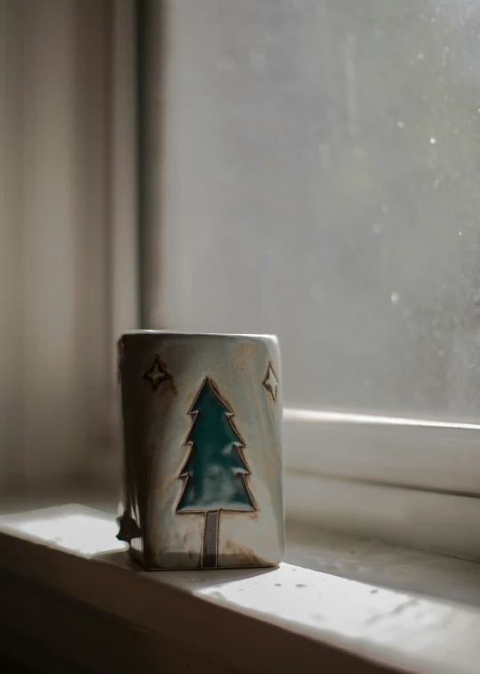 this is an image of a pottery cup sitting on a window sill